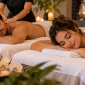 A man and a woman enjoy a romantic couples spa day while lying on massage tables and receiving back massages.