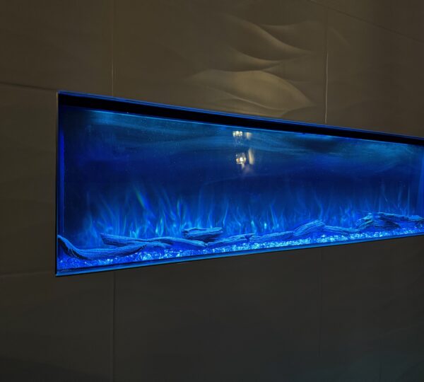 A rectangular electric fireplace with blue flames is set into a smooth, dark wall.