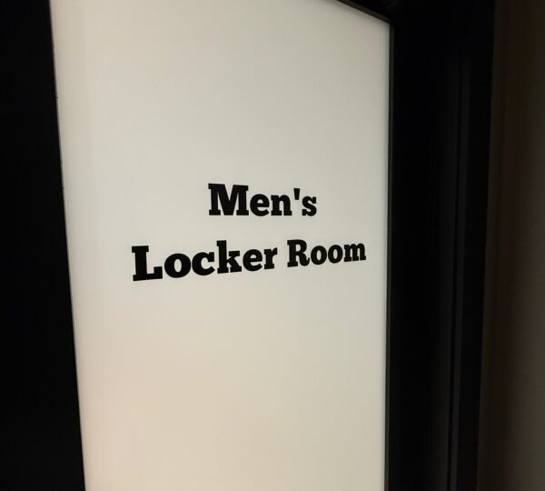 Frosted glass door with the words “Men’s Locker Room” in bold black letters.