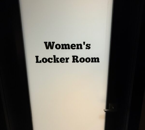 Frosted glass door with the words "Women's Locker Room" printed in bold black letters.