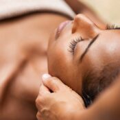 Person lying down with eyes closed while receiving a gentle neck massage, covered with a towel—a tranquil experience that’s often enjoyed in a Couples Massage session.
