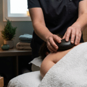 A massage therapist performs a hot stone massage on a client’s back.