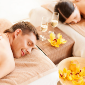 Two people enjoying a couples deep tissue massage on spa beds, with wine glasses and yellow flowers placed nearby—a perfect way to unwind and restore work-life balance.
